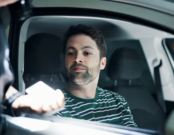 Conductor dentro del coche entregando la documentación a un agente de tráfico por una posible multa